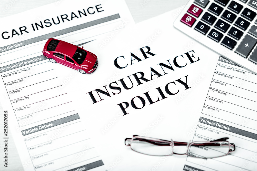 Car insurance policy. Document, model of car, glasses, calculator, pen and coins on table. Business and insurance background light concept.