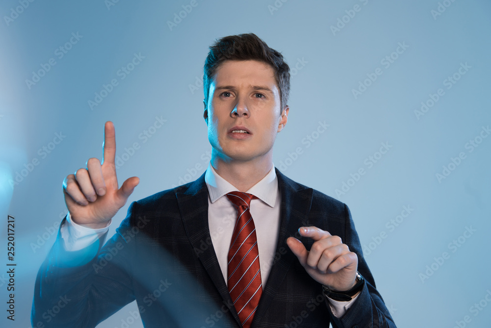 selective focus of young businessman touching something on blue selective focus of young businessman touching something on blue