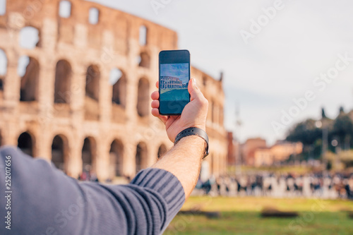 Photography Male hand with smartphone taking picture of colosseum (Rome, Italy)