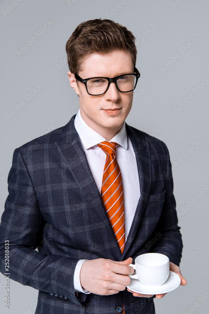 handsome stylish businessman holding cup of coffee isolated on grey handsome stylish businessman holding cup of coffee isolated on grey