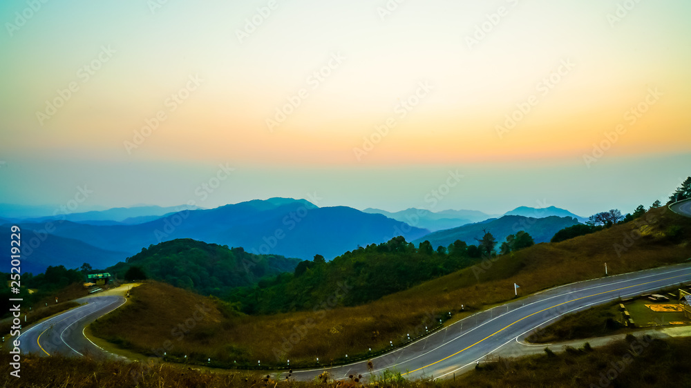 beautiful sunset sky with layer mountain and road
