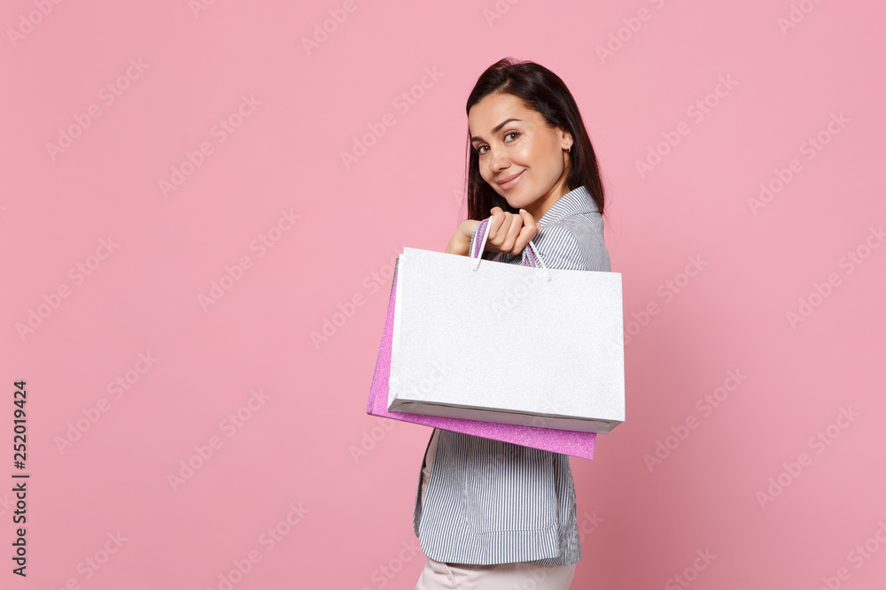 Portrait of pretty young woman in striped jacket holding package bag with purchases after shopping isolated on pink pastel background. People sincere emotions, lifestyle concept. Mock up copy space. Portrait of pretty young woman in striped jacket holding package bag with purchases after shopping isolated on pink pastel background. People sincere emotions, lifestyle concept. Mock up copy space.
