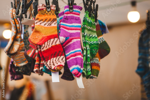 Colorful knitted traditional european warm clothes for cold winter days - close-up view. Children socks at winter Christmas market are lovely souvenir for tourists from Europe.
