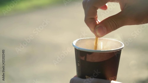 man stear hot tea in the cup in the morning outdoors, close up, 4k photo