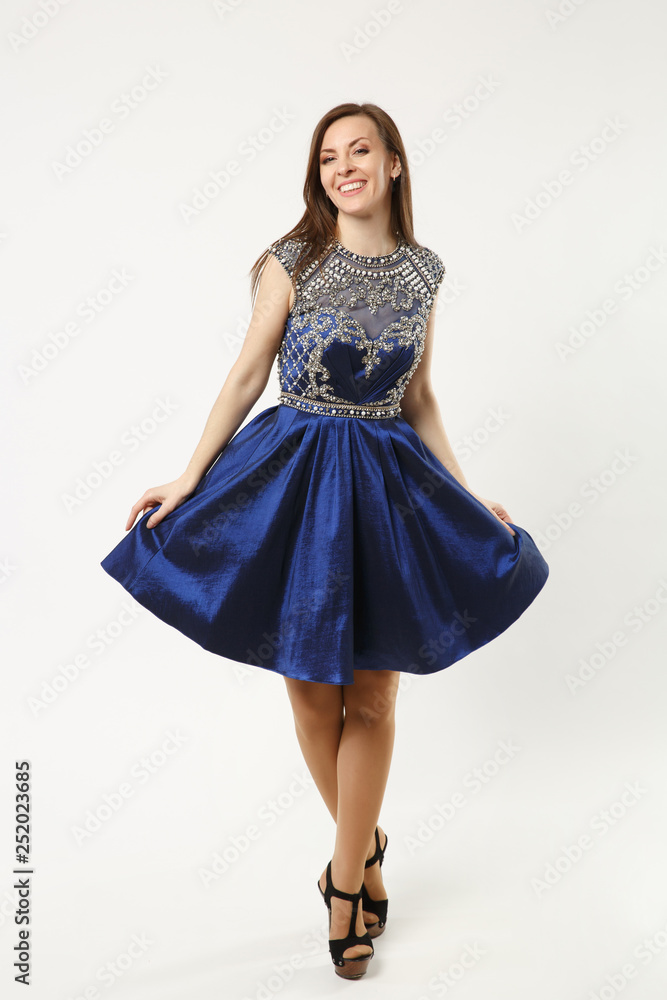 Full length photo of fashion model woman wearing elegant evening dress gown posing isolated on white wall background studio portrait. Brunette long hair girl. Mock up copy space. Blue dress face view. Full length photo of fashion model woman wearing elegant evening dress gown posing isolated on white wall background studio portrait. Brunette long hair girl. Mock up copy space. Blue dress face view.