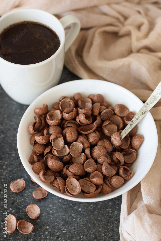 Chocolate dry breakfast in a white bowl with a cup of coffee Chocolate dry breakfast in a white bowl with a cup of coffee