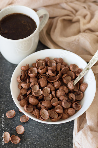 Chocolate dry breakfast in a white bowl with a cup of coffee