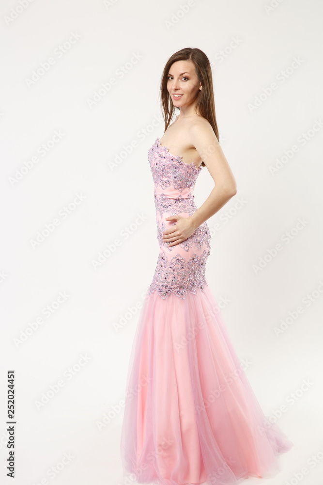 Full length photo fashion model woman wearing elegant evening dress pink gown posing isolated on white wall background studio portrait. Brunette long hair girl. Mock up copy space. Side profile view.