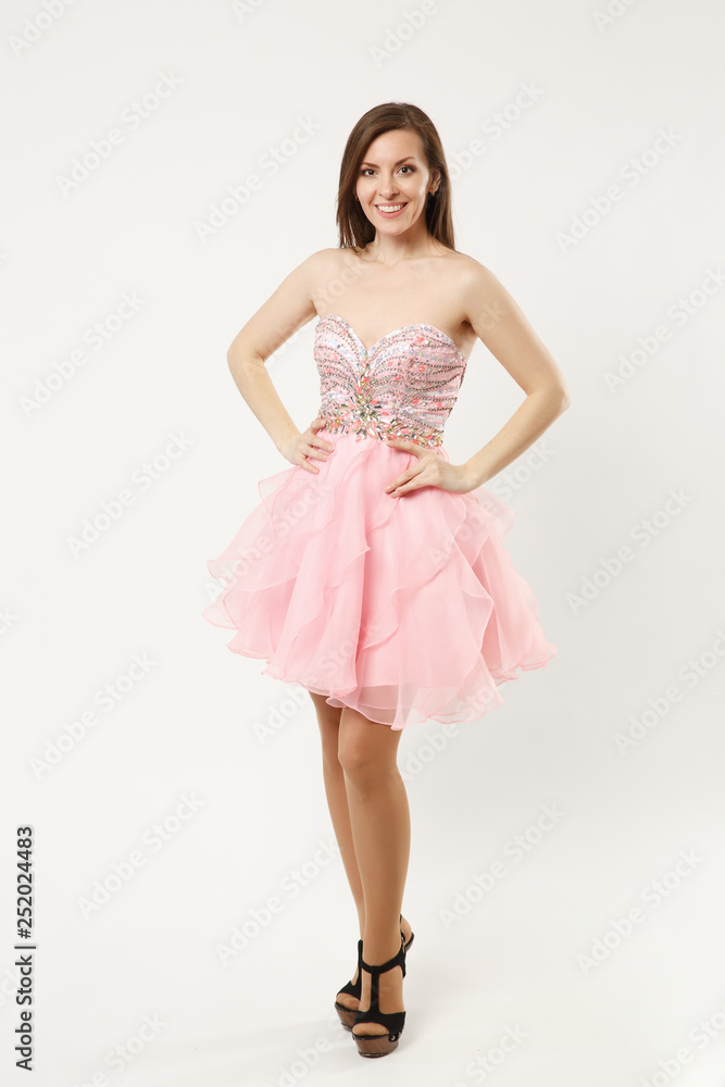 Full length photo of fashion model woman wearing elegant evening dress gown posing isolated on white wall background studio portrait. Brunette long hair girl. Mock up copy space. Pink dress face view.