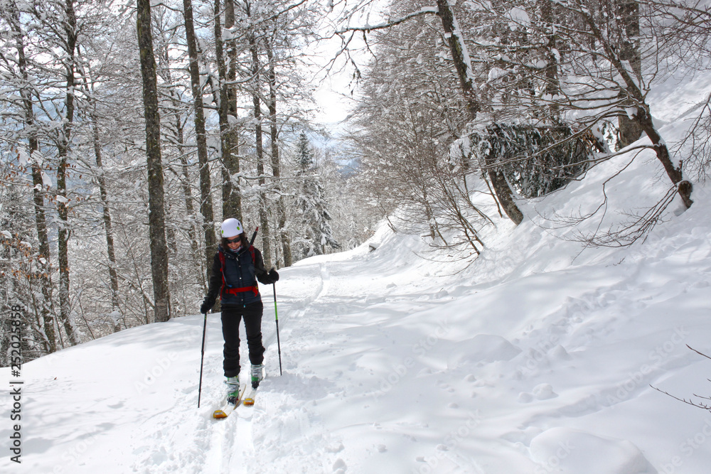 girl doing touring ski between trees in a mountain