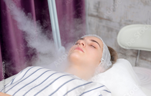 Obraz na plátne Beauty treatment of young female face, ozone facial steamer