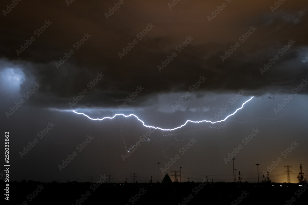 A horizontal lightning bolt cuts the sky below the clouds. A cloud to cloud CC lightning discharge near the city of Rotterdam, The Netherlands.
