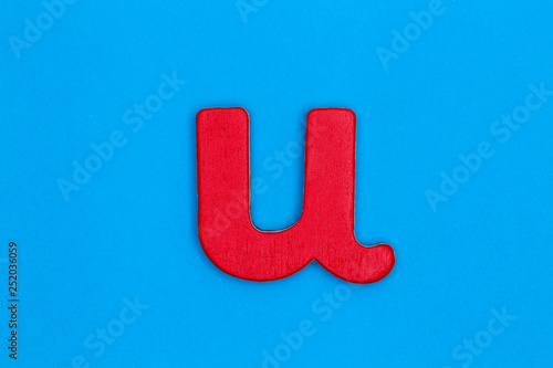 Wooden letter u painted red on a blue background