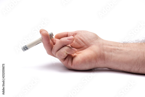 Conceptual image of smoking and money cost. STOP Smoking. Close up Man hand holding hundred dollar rolled in cigarette shape form.