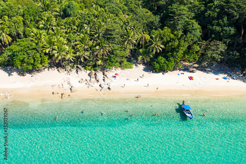 View from above, aerial view of a beautiful tropical beach with white sand, turquoise clear water, long-tail boat and people sunbathing, Banana beach, Phuket, Thailand.