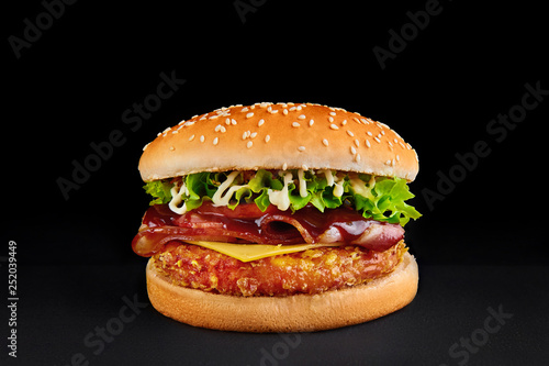 perfect burger with cutlet, cheese, bacon, tomato, lettuce isolated at black background