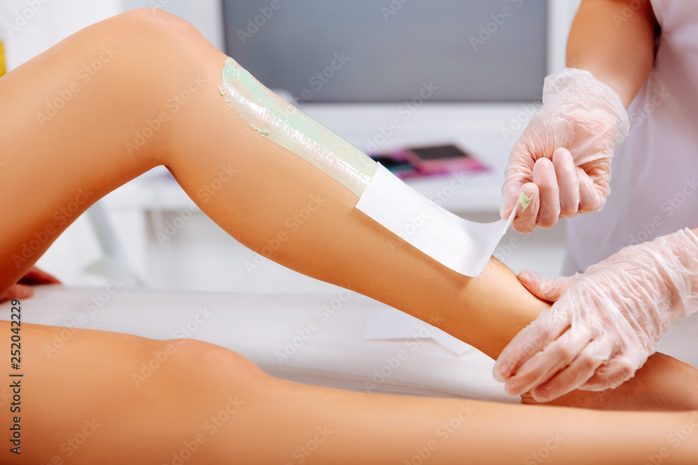 Fototapeta premium Professional wearing white jacket making wax depilation