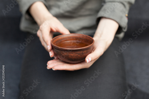 Woman offers hot tea in a vintage ceramic cup.