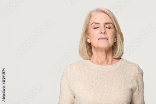 Calm mid aged woman breathing fresh air isolated on background