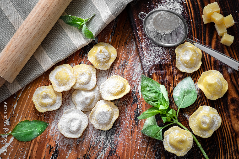 Ravioli with Parmesan and Basil on a wooden background with flour, top view, recipe concept
