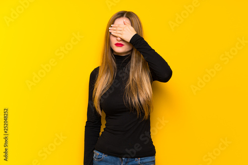 Young pretty woman over yellow background covering eyes by hands. Do not want to see something
