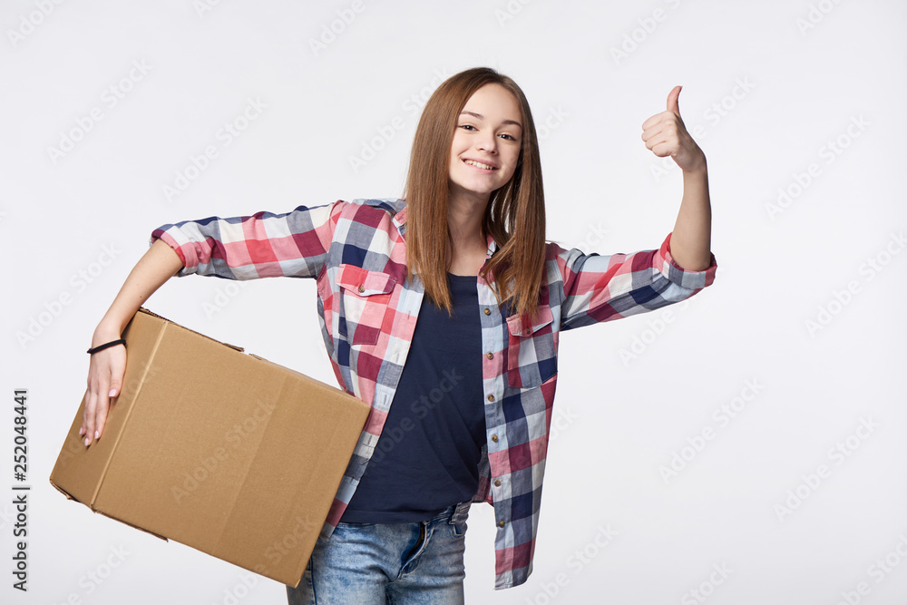 Happy girl holding cardboard box gesturing thumb up Happy girl holding cardboard box gesturing thumb up