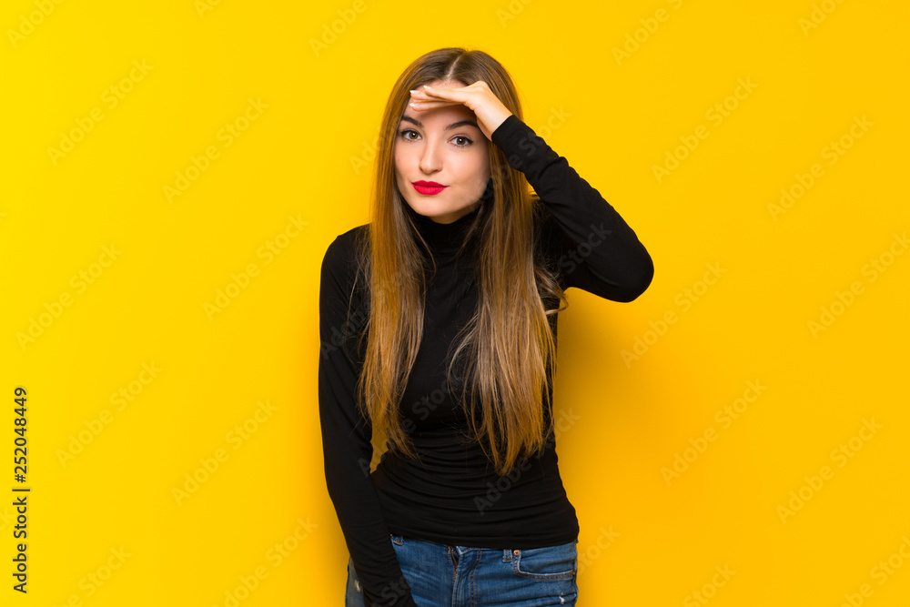 Young pretty woman over yellow background looking far away with hand to look something Young pretty woman over yellow background looking far away with hand to look something