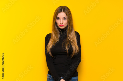 Young pretty woman over yellow background with sad and depressed expression