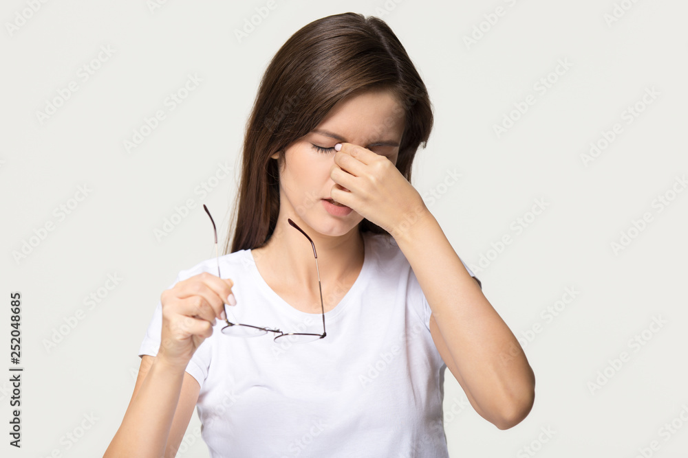 Tired girl taking off glasses feel eyestrain isolated on background Tired girl taking off glasses feel eyestrain isolated on background