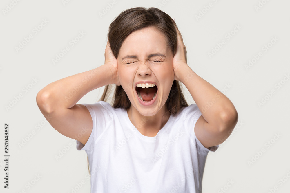 Angry crazy teen girl covering ears screaming isolated on background Angry crazy teen girl covering ears screaming isolated on background