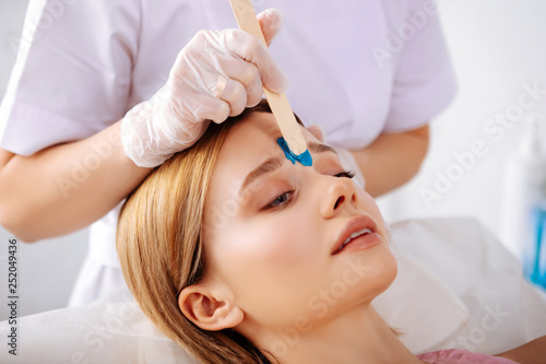 Close up of beauty specialist correcting form of eyebrows
