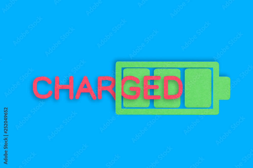 Handmade paper icon of full battery with green cells near red word charged in center of blue table. Top view. Technology concept Handmade paper icon of full battery with green cells near red word charged in center of blue table. Top view. Technology concept