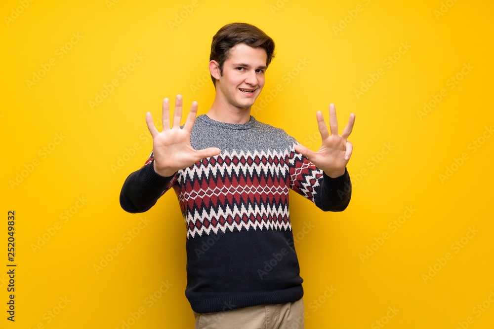 Teenager man over yellow wall counting nine with fingers Teenager man over yellow wall counting nine with fingers