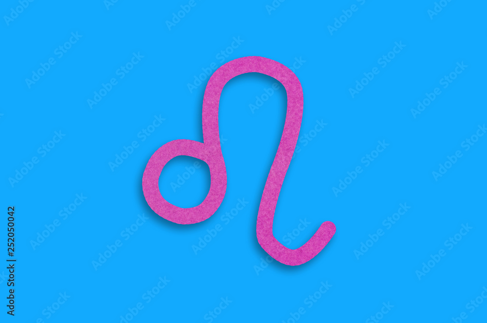Symbol of astrological sign leo cut out of purple paper in center on blue table. Top view. Horoscope concept Symbol of astrological sign leo cut out of purple paper in center on blue table. Top view. Horoscope concept
