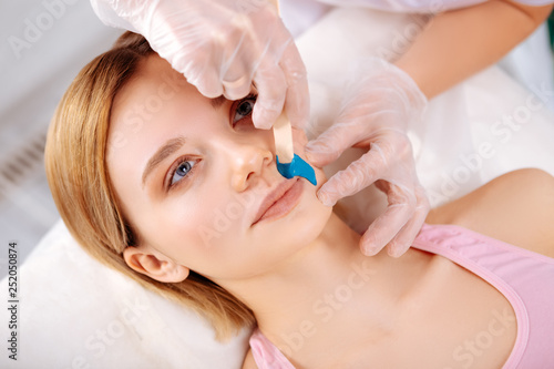 Specialist waxing line under nose of her constant client