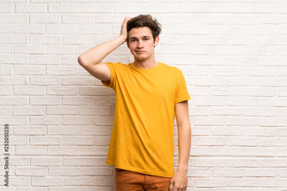 Teenager man over white brick wall with an expression of frustration and not understanding Teenager man over white brick wall with an expression of frustration and not understanding