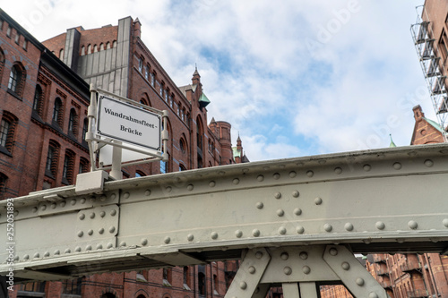 part of a steel bridge with brick buildings, blue sky and clouds in background photo