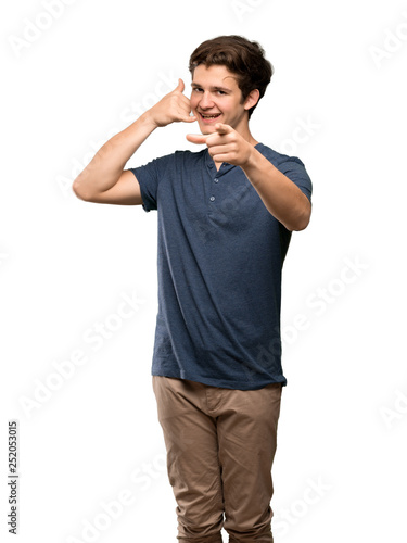 Teenager man making phone gesture and pointing front over isolated white background