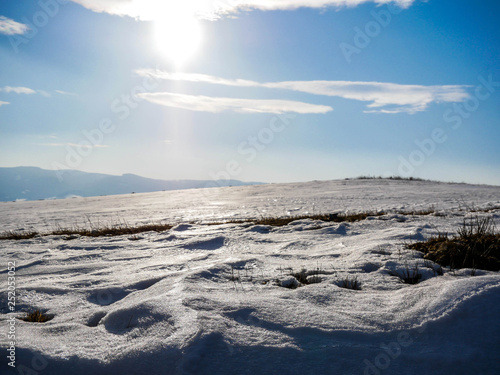 Frozen snow on the top of the hill , visible sun on blue sky. © Alpar