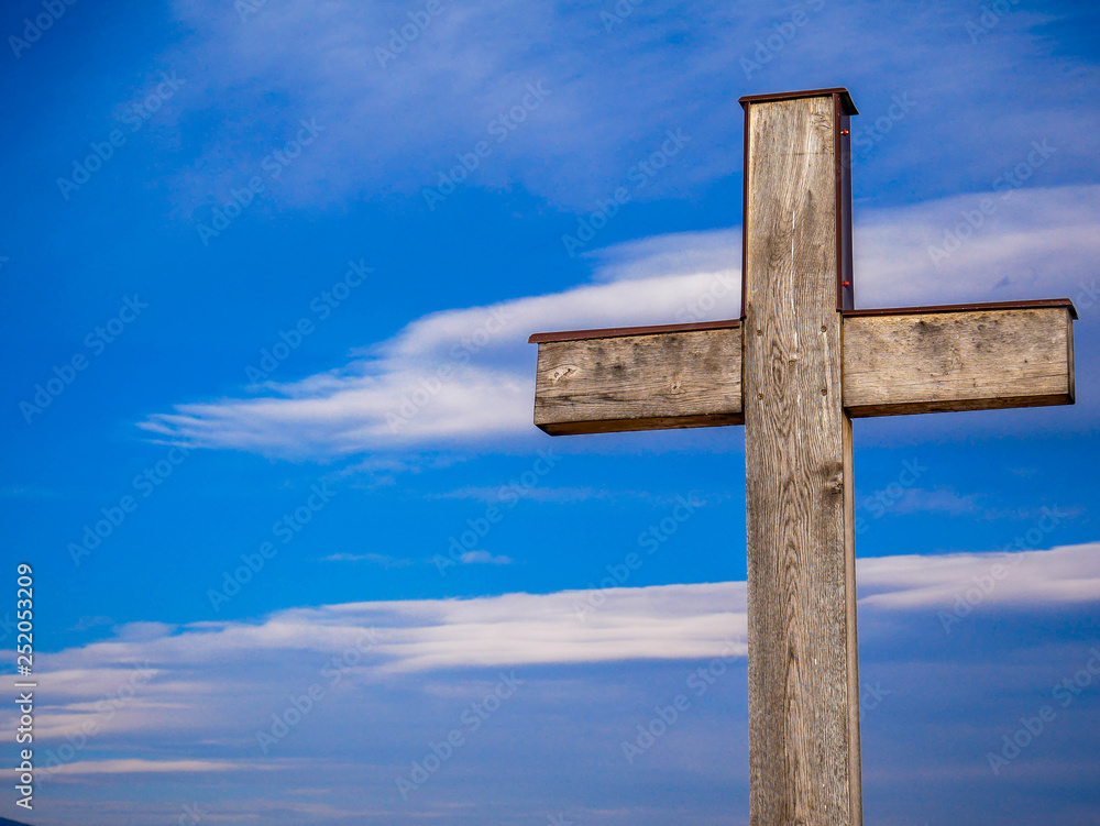 Simple wood catholic cross, blue sky with white clouds background, copy space. Simple wood catholic cross, blue sky with white clouds background, copy space.