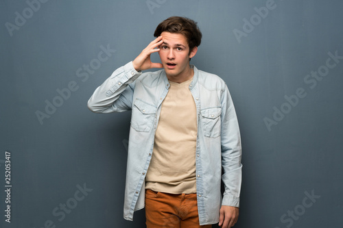 Teenager man with jean jacket over grey wall has just realized something and has intending the solution