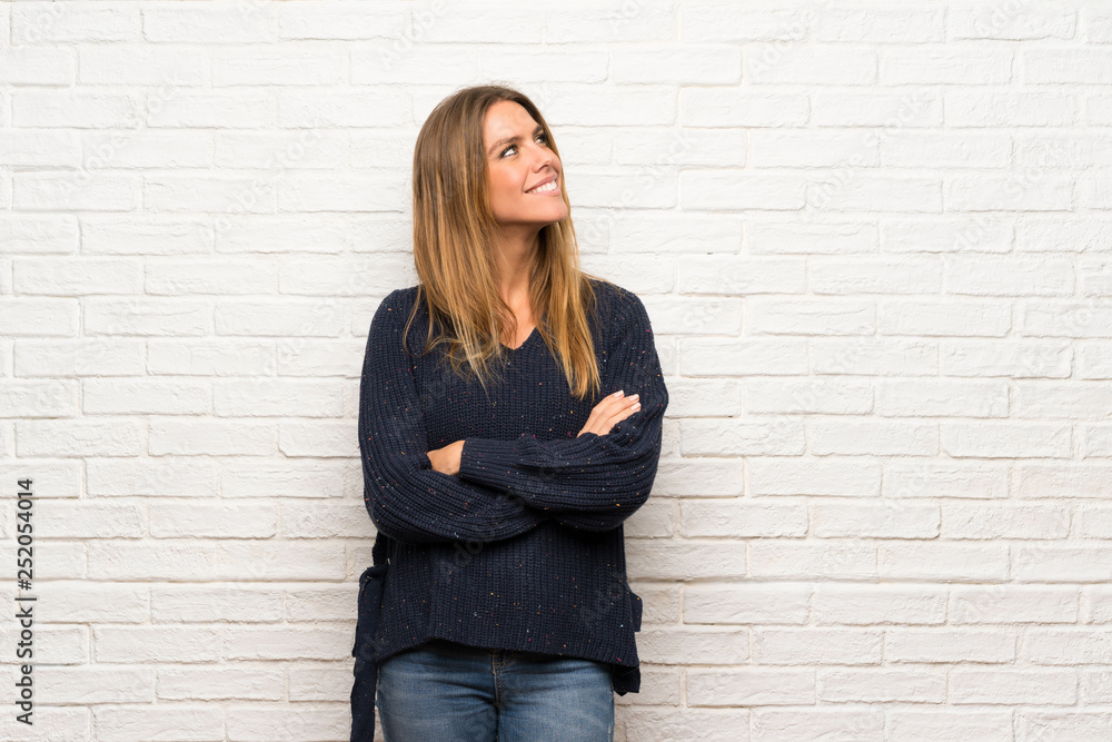 Blonde woman over brick wall looking to the side Blonde woman over brick wall looking to the side