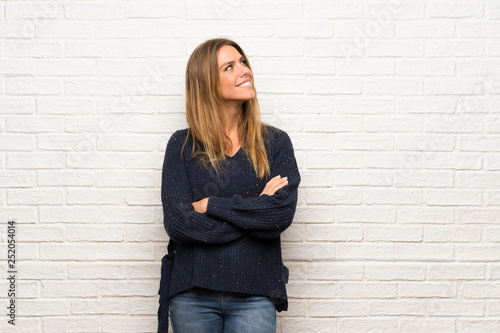 Blonde woman over brick wall looking to the side