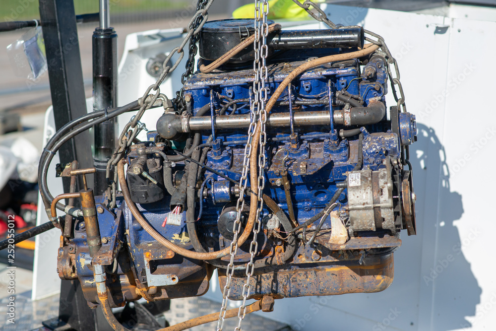 blue engine block being lifted from boat by pulley and chain using lifting equipment blue engine block being lifted from boat by pulley and chain using lifting equipment
