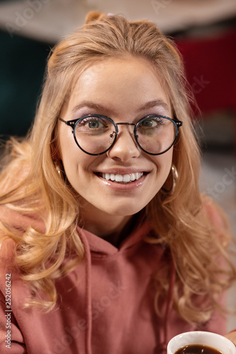 Close up portrait of young Caucasian woman looking through the camera and smiling beamingly. photo