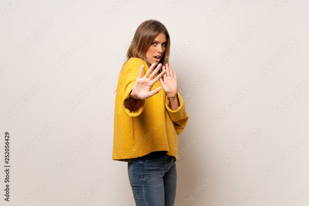 Woman with yellow sweater over isolated wall nervous and scared stretching hands to the front Woman with yellow sweater over isolated wall nervous and scared stretching hands to the front