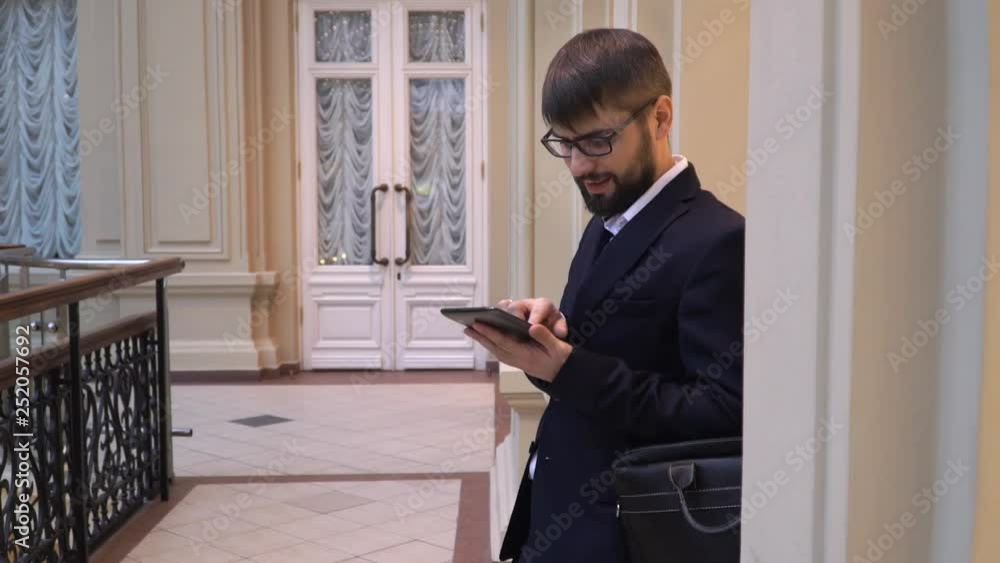 Young attractive man in glasses with a beard is using a mobile phone. Work, business Young attractive man in glasses with a beard is using a mobile phone. Work, business