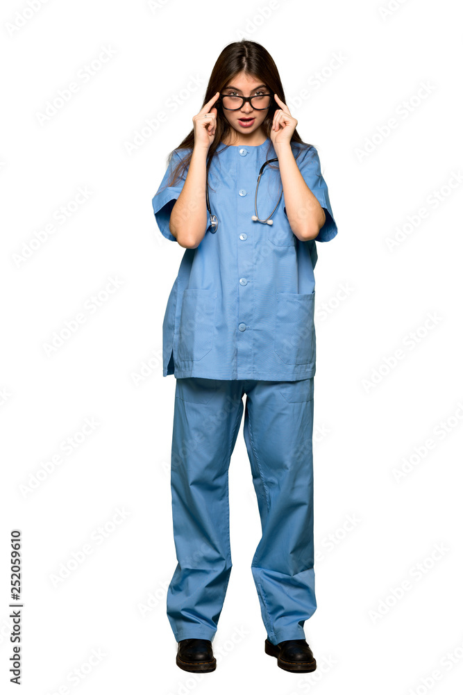 Full-length shot of Young nurse with glasses and surprised on isolated white background Full-length shot of Young nurse with glasses and surprised on isolated white background