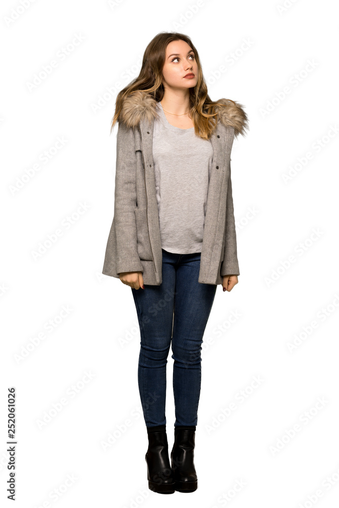 A full-length shot of a Teenager girl with coat looking up with serious face on isolated white background A full-length shot of a Teenager girl with coat looking up with serious face on isolated white background