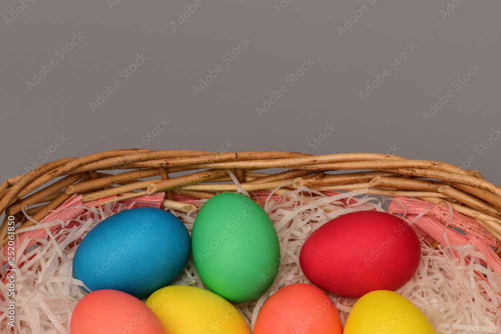Naklejka premium Top view of Easter eggs in basket on grey background. Horizontal photography